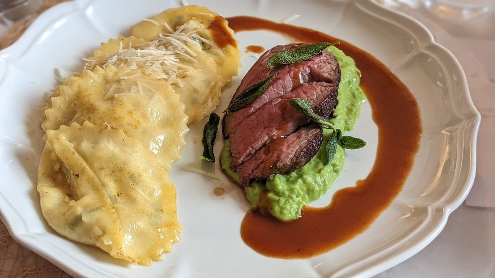 Pink-seared duck breast on pea purée with ricotta cream cheese ravioli and duck jus